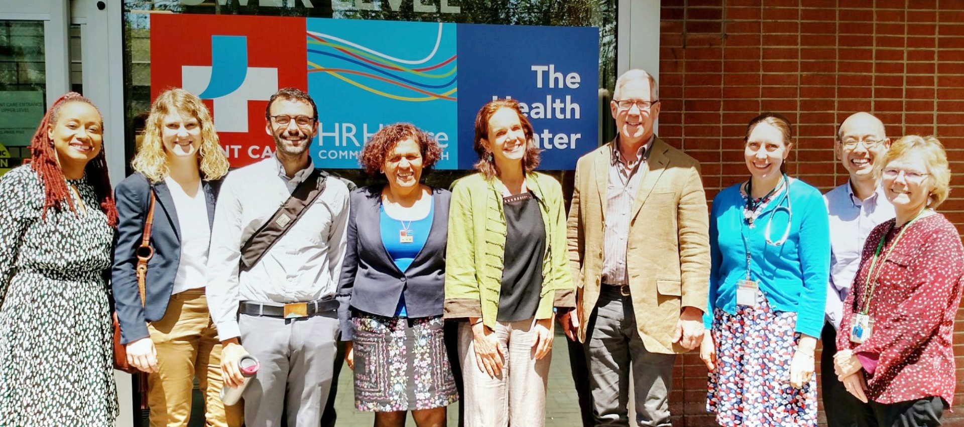 SIG team posing in front of the Health Center on a sunny day