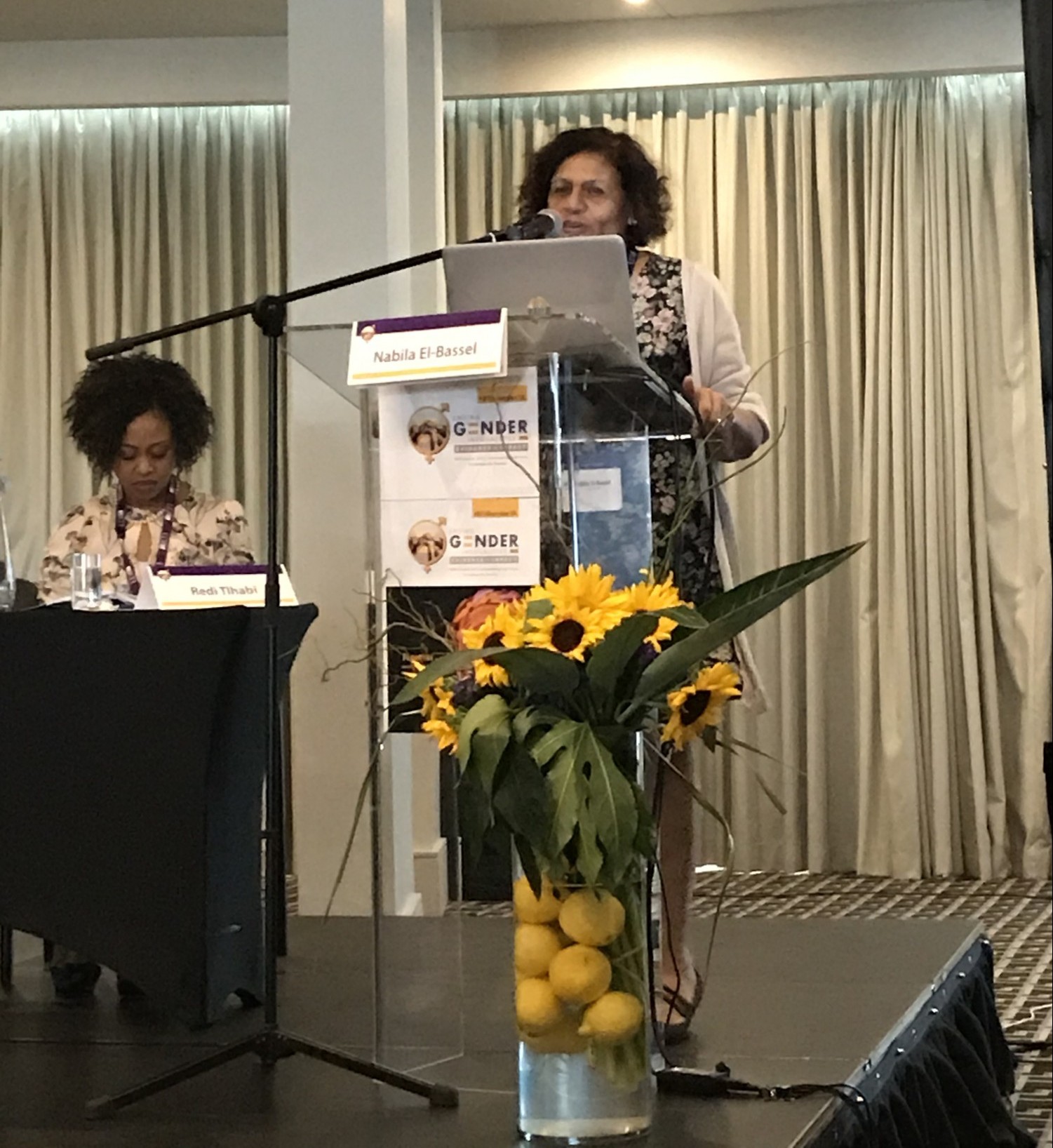 Dr. El-Bassel presents her keynote Nabila presenting at a podium