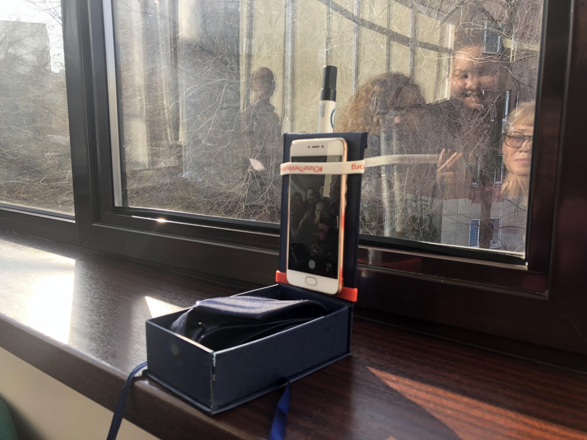 a smartphone taped to a box and window as a stand