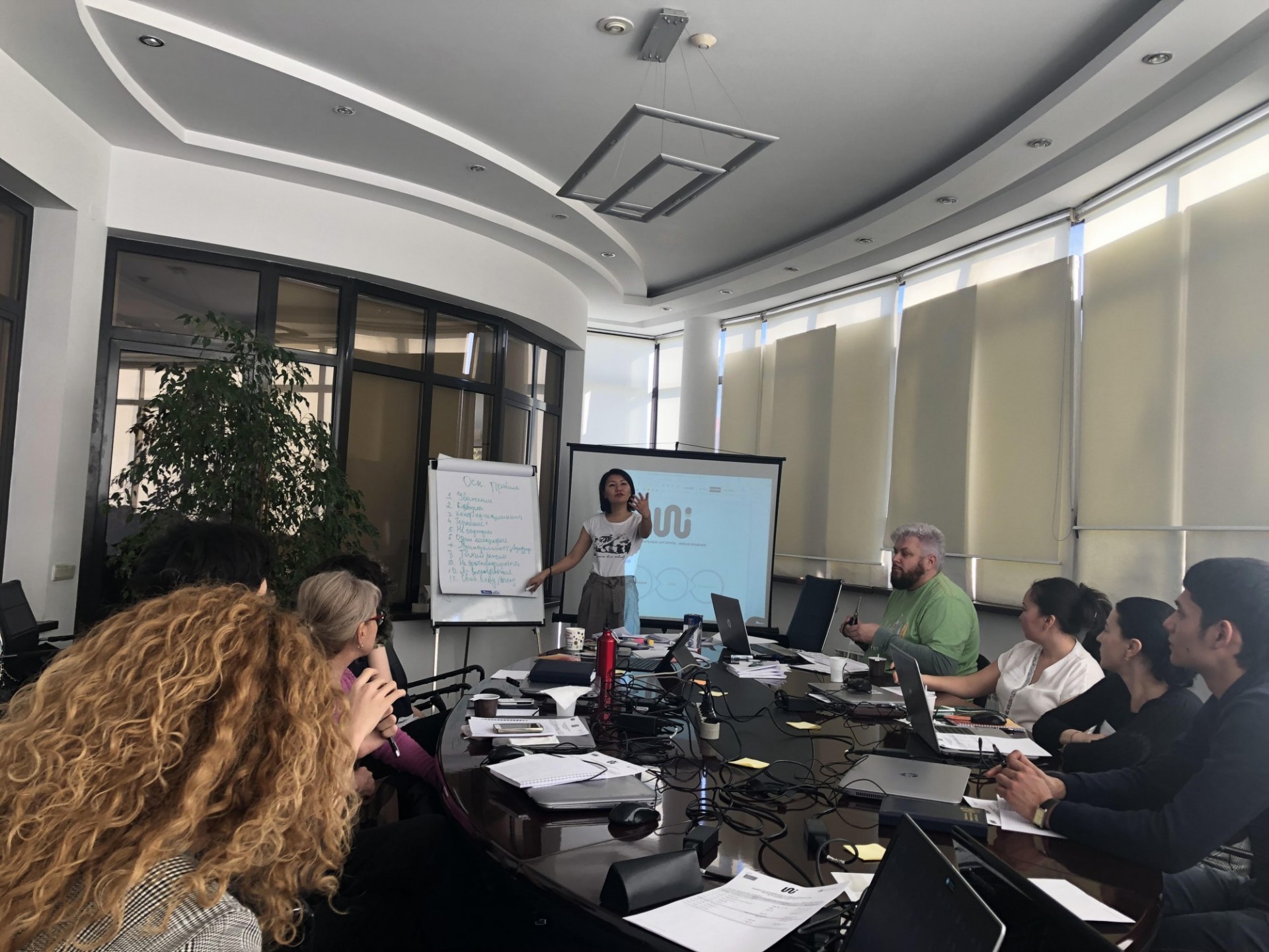 UNI Project Director, Gulnara Zhakupova, facilitating establishment of ground rules; Project Coordinator Vitaliy Vinogradov sits to the right of Ms. Zhakupova Project director speaking to facilitatators at a table meeting