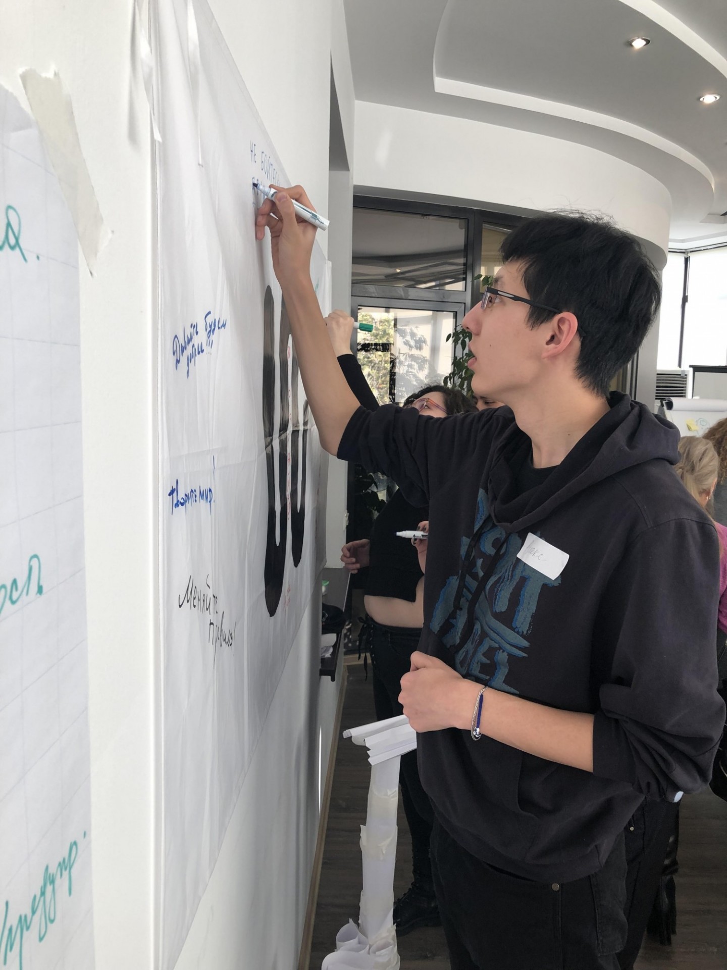 UNI Research Assistant, Aidar Yelkeyev, writes words of encouragement Staff writing an encouraging message on a paper on the wall