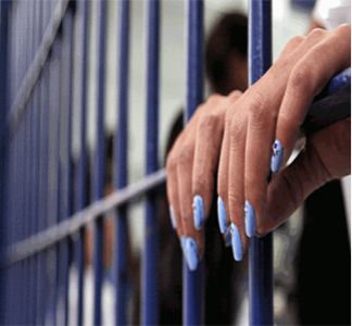 Woman's hands behind bars, stock photo