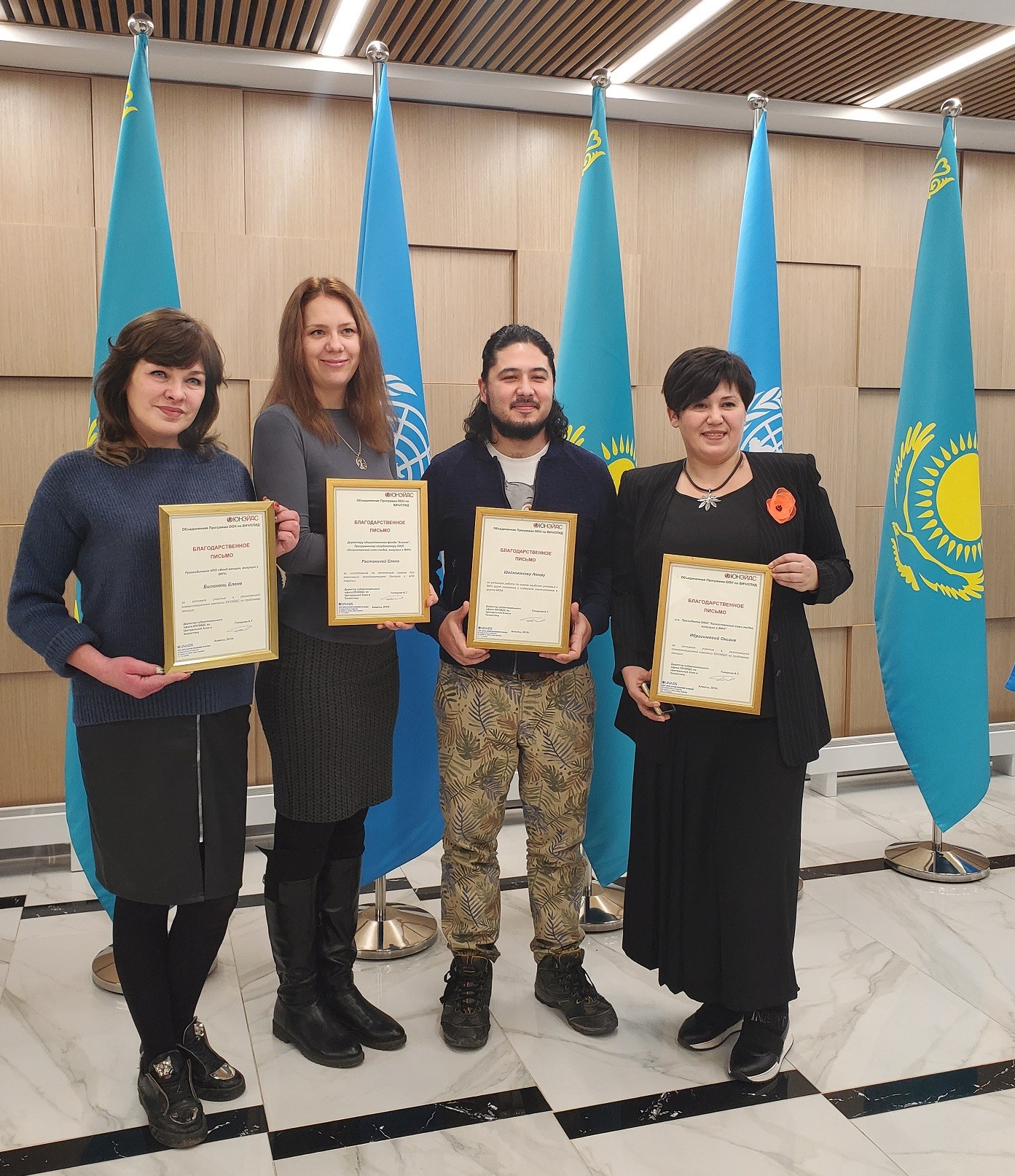 Amir Shaykezhanov (2nd from the right), GHRCCA collegue who works on the UNI project and Be Online, receiving an award from UNAIDS for his work on HIV among men who have sex with men. People standing in front of flags inside holding their awards