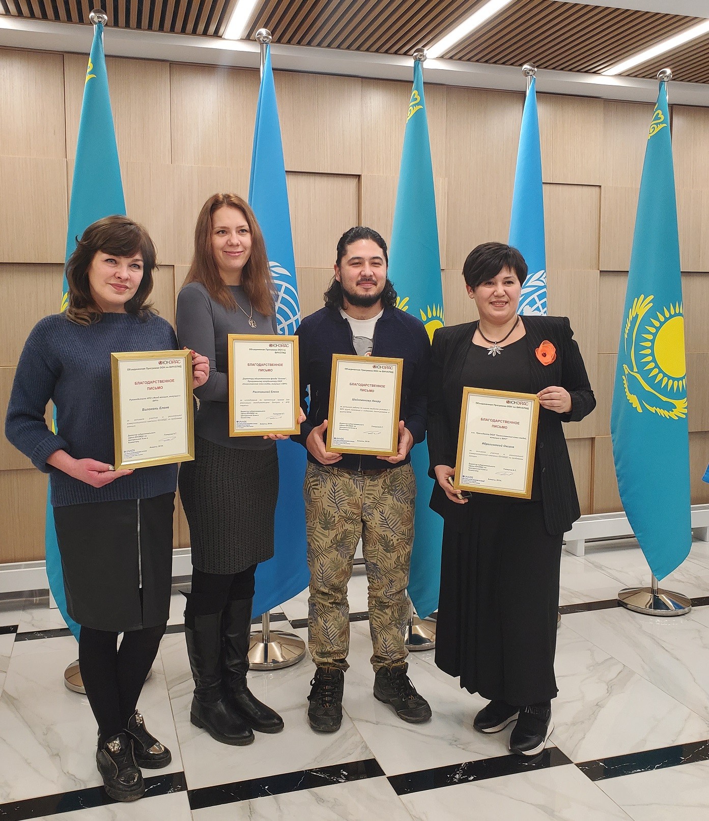 People standing in front of flags inside holding their awards