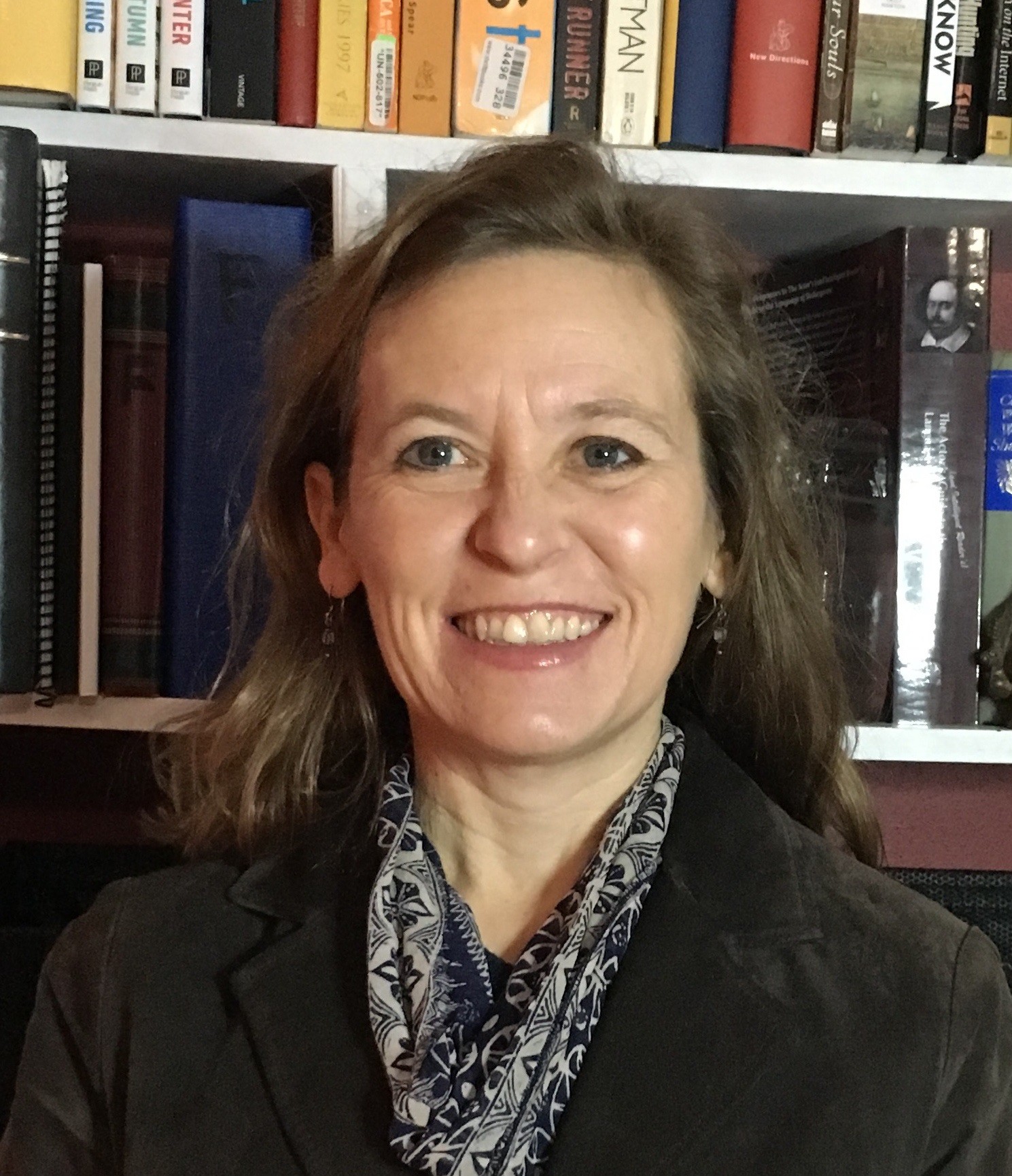 Photo of dr. Marguerite Burns, smiling in front of books