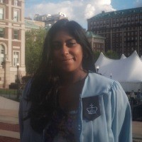 A woman with long dark hair wearing a Columbia graduation gown