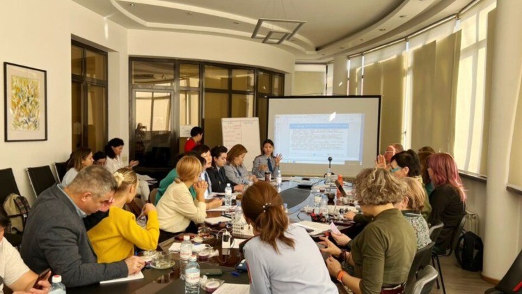 A group of people around a table watching a presentation