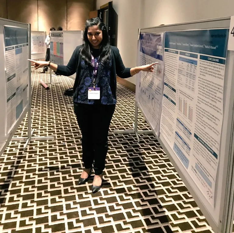 Anindita standing between her research posters, smiling
