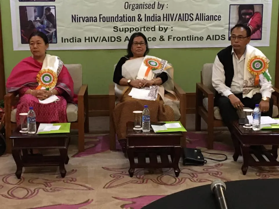 three people sit in front of a conference sign presenting