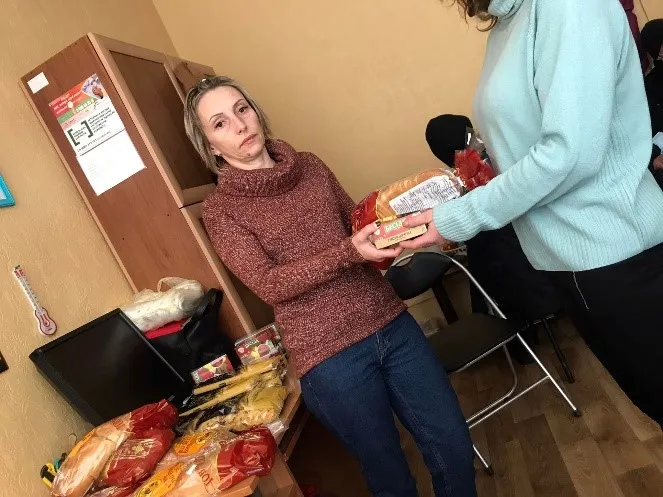 A woman receives humanitarian aid. Club Eney has relied on deep community connections to quickly distribute food and hygiene products in wartime.