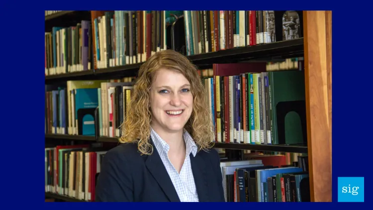 a woman in a suit jacket in front of a library shelf