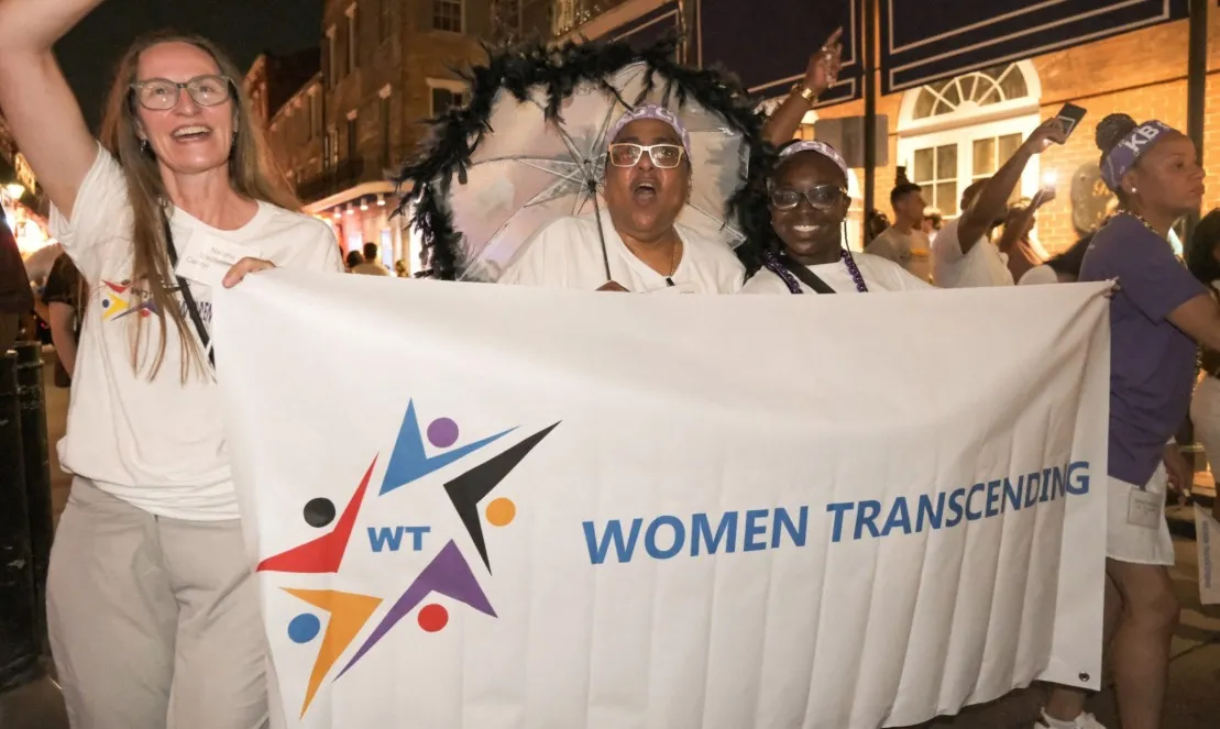 Women holding a banner that says "Women Transcending"