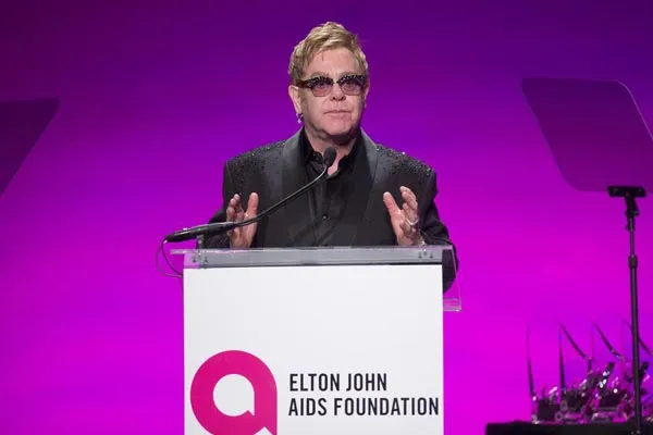 Elton John presenting at a podium for his foundation