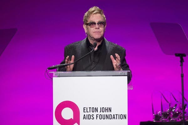 Elton John presenting at a podium for his foundation