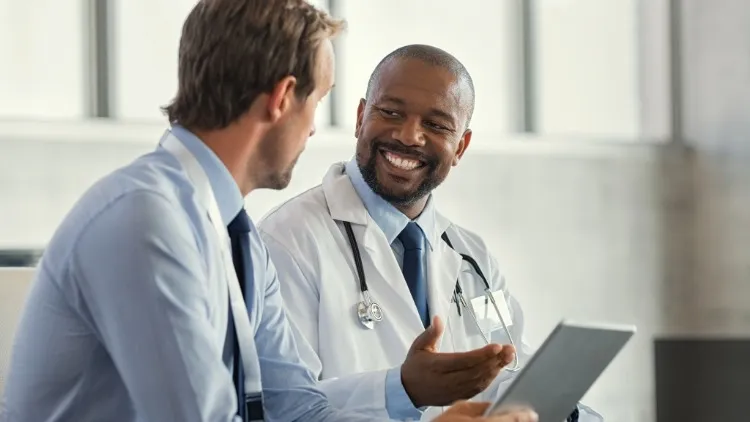 A doctor shows an an iPad to another man