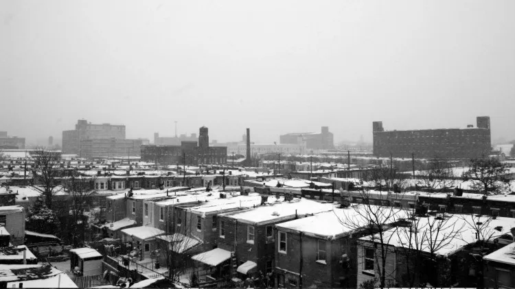 A black and white image of two story homes with factories in the background